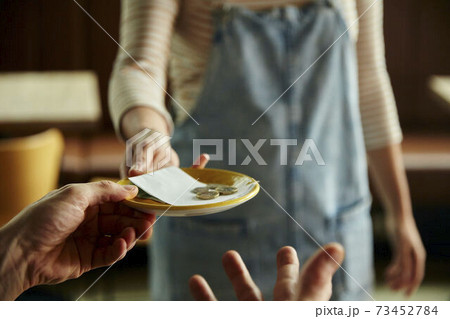Woman holding out a plate with a cafe bill and coins. 73452784