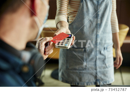 Woman holding contactless payment terminal for a customer paying by card 73452787