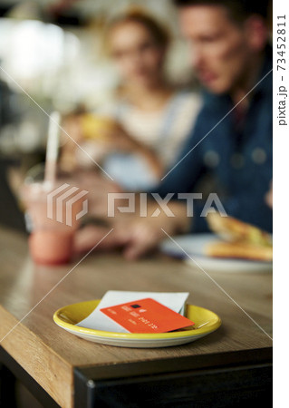 People at a cafe table, a saucer with till receipt and credit card. 73452811