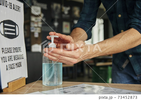 Man using hand sanitiser gel in restaurant 73452873