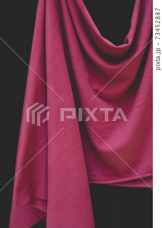 Detail of hanging pink fabric against black background 73452887