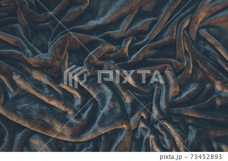 Detail of draped and crumpled velvet fabric, moody warm lighting illuminating wrinkles and creases 73452893