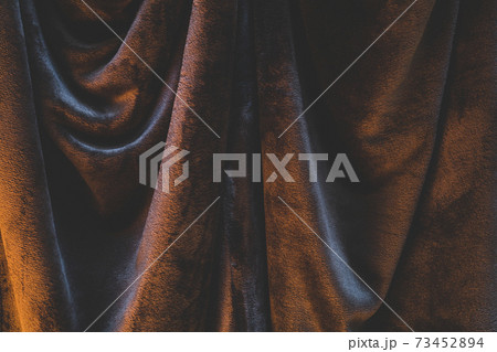 Detail of draped and crumpled velvet fabric, moody warm lighting illuminating wrinkles and creases 73452894
