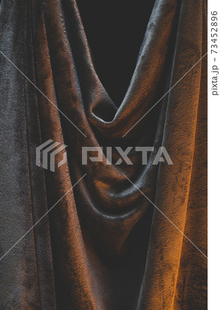 Detail of draped and crumpled velvet fabric, moody warm lighting illuminating wrinkles and creases 73452896