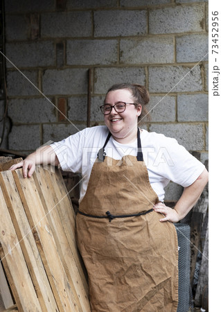 Portrait of female baker outdoors, hand on hip, smiling at camera. 73452956
