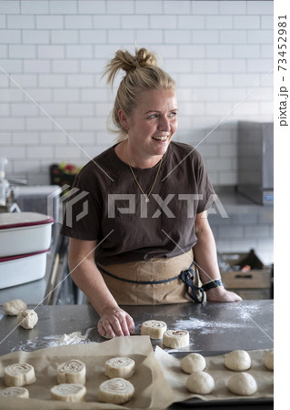 Woman working in a kitchen, preparing danish pastries dough. 73452981