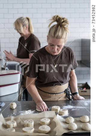 Woman working in a kitchen, preparing danish pastries dough. 73452982