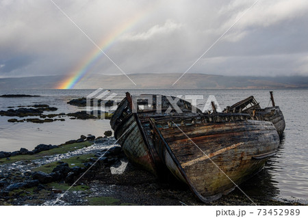 Rainbow and beached old wooden fishing boats on shore at Salen Rainbow and beached old wooden fishing boats on shore at Salen 73452989