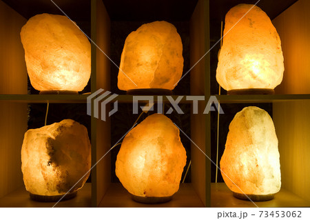 Lit up salt crystal lamps on shelves 73453062