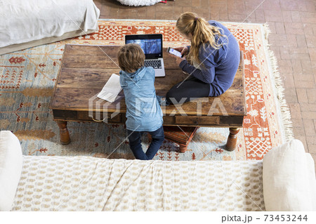 overhead view of teenage girl and her younger brother using laptop and smart phone 73453244