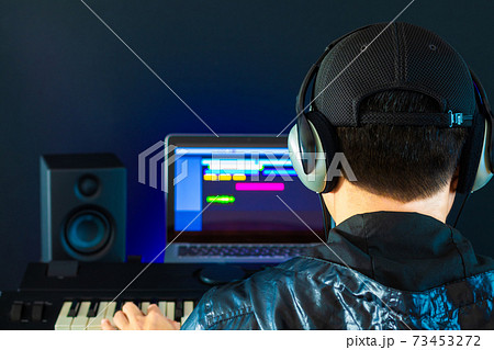 back of asian professional male music producer, sound engineer arranging a song on midi keyboard, laptop computer. music production concept 73453272