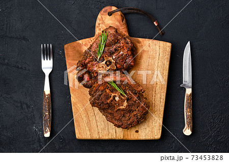 Overhead view of grilled lamb neck on wooden cutting board 73453828