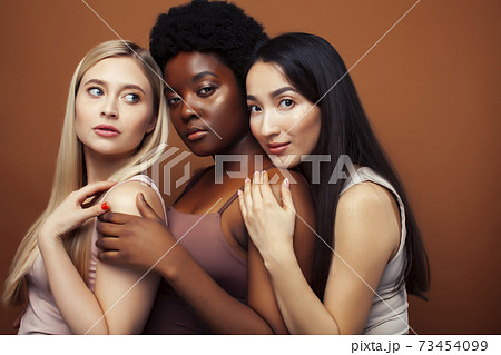 young pretty asian, caucasian, afro woman posing cheerful together on brown background, lifestyle diverse nationality people concept young pretty asian, caucasian, afro woman posing cheerful together on brown background, lifestyle diverse nationality people concept 73454099