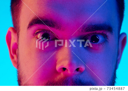 Caucasian man's portrait isolated on blue studio background in neon light. Concept of human emotions, facial expression, sales, ad. 73454887