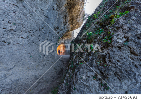 Two unrecognizable persons walking through the rocks tunnel 73455693