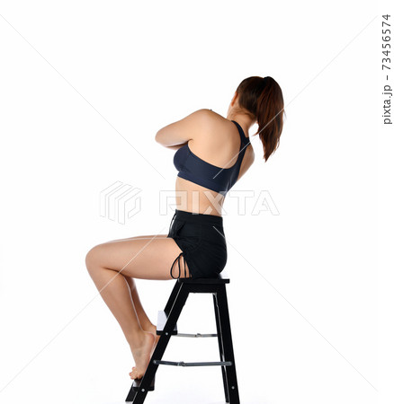 Athletic girl sitting on a chair with her back to the camera. 73456574