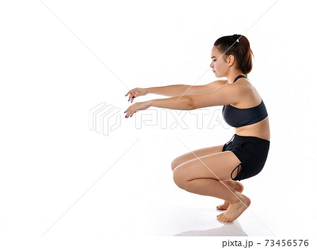 Young focused woman doing fitness exercise, isolated on white background. 73456576