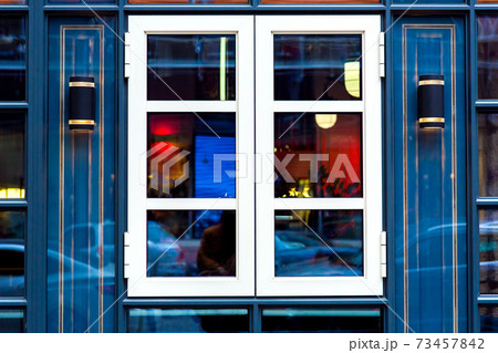 The glass facade of the building is blue with a white window and luminous decorative lanterns in black. 73457842