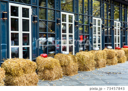 The facade of the building with windows with lanterns and haystacks near the building and taverns for the autumn holiday Halloween. The facade of the building with windows with lanterns and haystacks near the building and taverns for the autumn holiday Halloween. 73457843