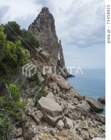 View of Pedra Longa, limestone rock pillar at coast Gulf of Orosei, beginning of the famous and difficult hiking climbing trail Selvaggio blu, wild blue, Sardinia, Italy 73458925