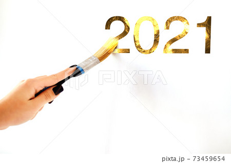 Close-up of a woman's hand with a brush drawing the Golden numbers 2021 Close-up of a woman's hand with a brush drawing the Golden numbers 2021 73459654