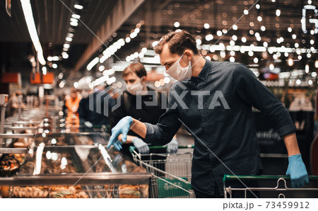 customer in protective gloves choosing products in a supermarket. 73459912