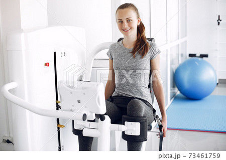 Young lady doing exercises on simulator in phisiotherapy room Young lady doing exercises on simulator in phisiotherapy room 73461759