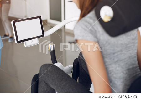 Young lady doing exercises on simulator in phisiotherapy room Young lady doing exercises on simulator in phisiotherapy room 73461778
