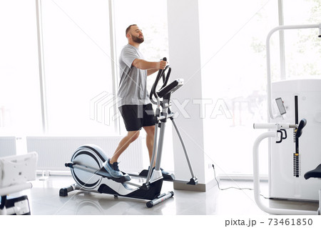 Bearded man using spin bike in physiotherapy room Bearded man using spin bike in physiotherapy room 73461850