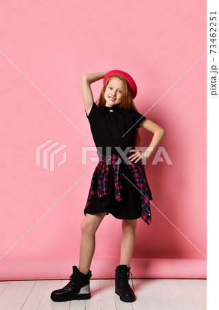 Ginger teenage girl in black dress, checkered shirt on waist, red hat and choker. She smiling, posing on pink background. Close up Ginger teenage girl in black dress, checkered shirt on waist, red hat and choker. She smiling, posing on pink background. Close up 73462251