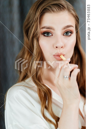 beautiful young woman with long hair and makeup eating French fries. beautiful young woman with long hair and makeup eating French fries. 73463883