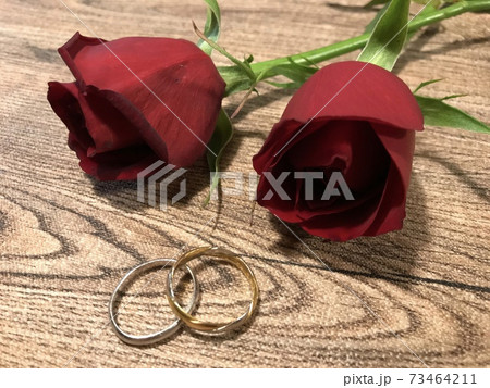 木目のテーブルに置かれた赤いバラと結婚指輪、結婚、婚約、婚活イメージ 木目のテーブルに置かれた赤いバラと結婚指輪、結婚、婚約、婚活イメージ 73464211