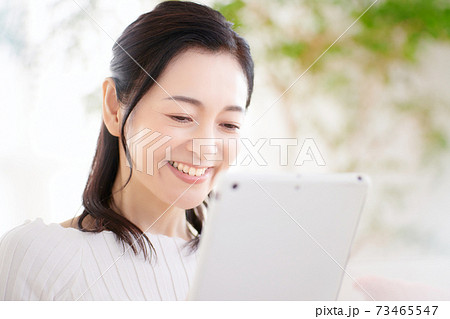 リビングでタブレットを操作するミドルの女性 73465547