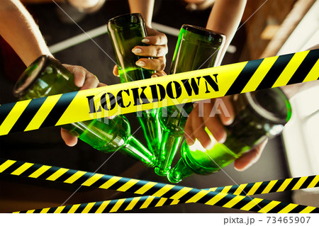 Close up hands clinking bottles of beer at bar with bounding tapes Lockdown, Coronavirus, Quarantine, Warning - closing bars and nightclubs during pandemic Close up hands clinking bottles of beer at bar with bounding tapes Lockdown, Coronavirus, Quarantine, Warning - closing bars and nightclubs during pandemic 73465907