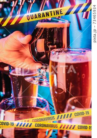 Hand of bartender pouring a beer in tap with bounding tapes Lockdown, Coronavirus, Quarantine, Warning - closing bars and nightclubs during pandemic 73465934