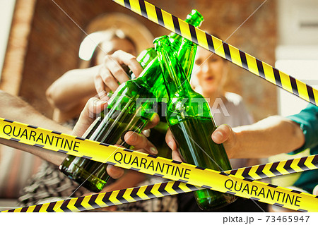 Close up hands clinking bottles of beer at bar with bounding tapes Lockdown, Coronavirus, Quarantine, Warning - closing bars and nightclubs during pandemic Close up hands clinking bottles of beer at bar with bounding tapes Lockdown, Coronavirus, Quarantine, Warning - closing bars and nightclubs during pandemic 73465947