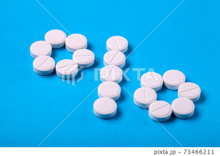Symbol percent laid out from white round pills on blue background, close-up designation of discounts and sales. 73466211