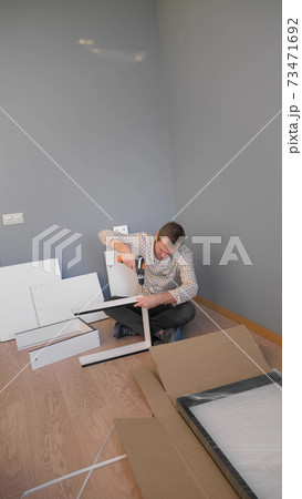 handsome man collects furniture at home in the room. copy space handsome man collects furniture at home in the room. copy space 73471692