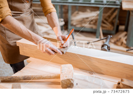 Carpenter working with a wood indoors 73472675