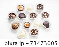 Different chocolate pralines. Belgian pralines of different shapes in paper baskets 73473005