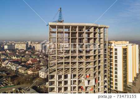 Aerial view of concrete frame of tall apartment building under construction in a city. 73473155