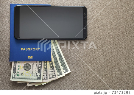 Modern black cellphone, money dollars banknotes bills and travel passport on copy space background. Travelling light, comfortable journey concept. 73473292