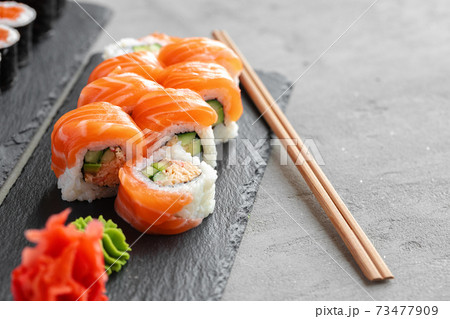 Sushi roll covered with fresh salmon served on plate Sushi roll covered with fresh salmon served on plate 73477909