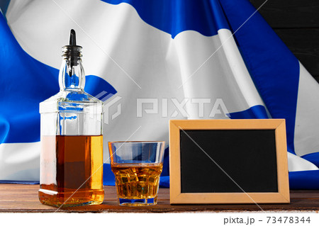 Bottle of whisky with slate board against flag of Scotland 73478344