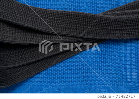 The view from the top. Kimono for judo classes and a black belt. The kimono is blue. Background, texture. The view from the top. Kimono for judo classes and a black belt. The kimono is blue. Background, texture. 73482717