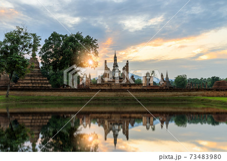 Buddha statue and pagoda Wat Mahathat temple with reflection during sun set, Sukhothai Historical Park, Thailand Buddha statue and pagoda Wat Mahathat temple with reflection during sun set, Sukhothai Historical Park, Thailand 73483980