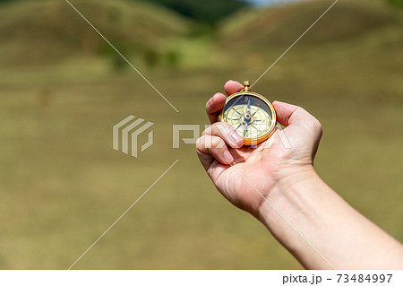 Compass in male traveler man hand in meadow Compass in male traveler man hand in meadow 73484997
