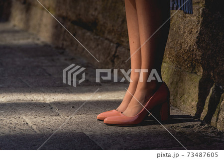 Young lady in beige leather heels standing on the pavement on the city street. Casual street fashion look. 73487605