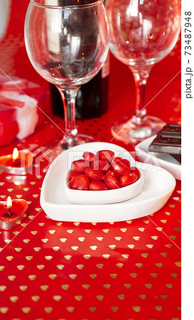 Valentines day. Bottle of vine, glasses, red roses, candles - red background Valentines day. Bottle of vine, glasses, red roses, candles - red background 73487948