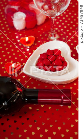 Valentines day. Bottle of vine, glasses, red roses, candles - red background Valentines day. Bottle of vine, glasses, red roses, candles - red background 73487949